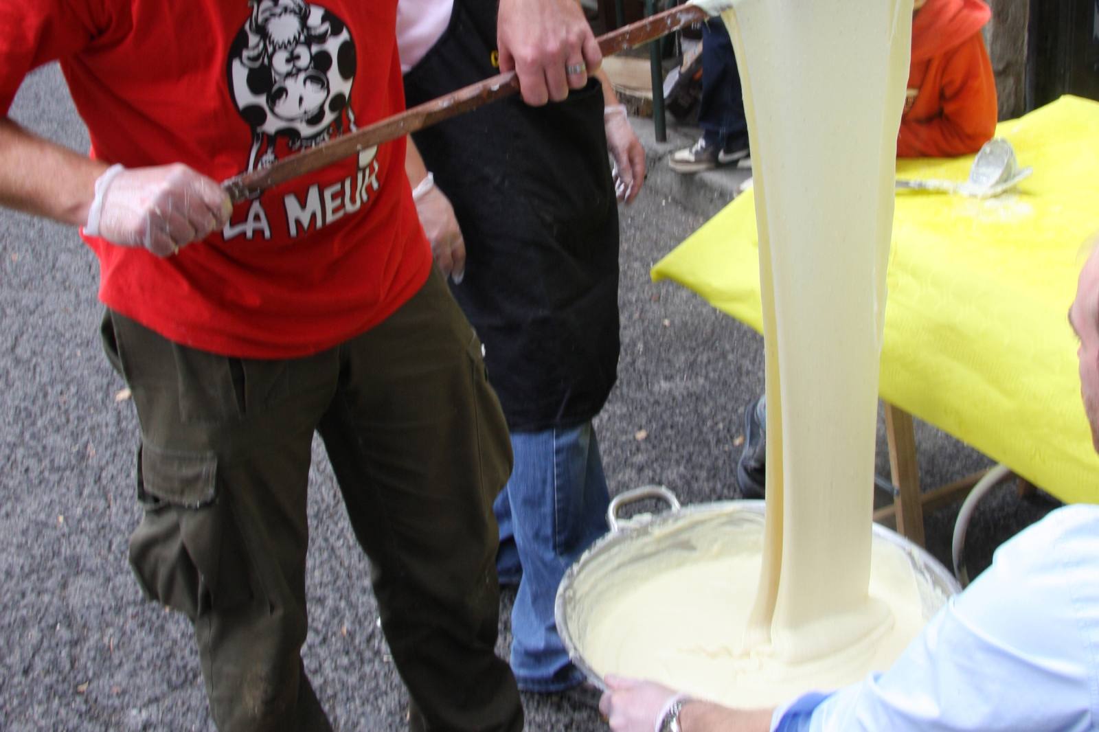 Aligot stretched with a ladle from a large pot, showing the elastic texture of melted fresh tome cheese