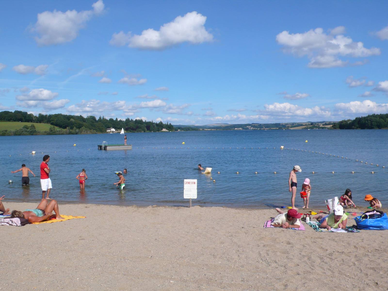 A family swimming at a lakeside beach on Lac de Pareloup, on the Lévézou plateau, Aveyron